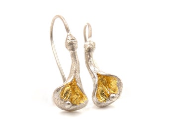 Puede incluir: Pendientes de plata con interior dorado, con forma de calas. Los pendientes tienen un acabado texturizado y un pequeño acento redondo cerca de la base de la flor. Los ganchos para las orejas son de plata.