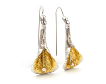 Puede incluir: Un par de pendientes de plata con detalles dorados. Los pendientes tienen forma de flor con una pequeña bola dorada en el centro.