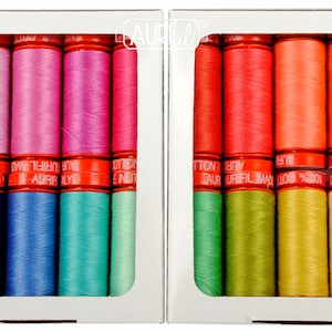 May include: Two boxes of colorful cotton thread spools. The spools are arranged in a rainbow gradient. The boxes are white with red text that reads "COTTON 100% MADE IN ITALY".