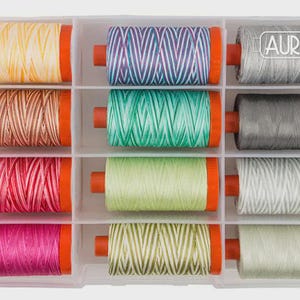 May include: A clear plastic organizer filled with spools of colorful thread. The thread colors include yellow, brown, pink, green, and gray. Each spool has orange end caps. The brand name "AURIfil" is visible on one spool.