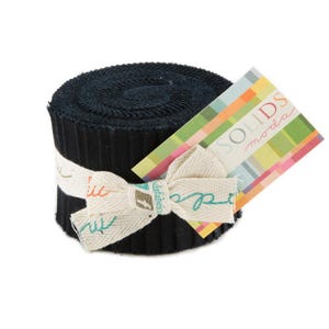 May include: A rolled bundle of black fabric strips, secured with a cream-colored ribbon tied in a bow. A colorful tag with the text "SOLIDS moda" is attached. The fabric appears to be cotton or a similar material.