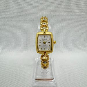 Reloj de pulsera vintage dorado para mujer, esfera rectangular blanca, correa de cadena con pedrería, elegante joyería retro, regalo chic atemporal.