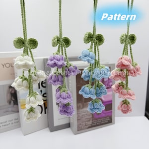 Puede incluir: Cuatro guirnaldas de flores de ganchillo en blanco, morado, azul y rosa. Cada guirnalda presenta una serie de flores de ganchillo con hojas verdes y una larga cuerda de ganchillo.