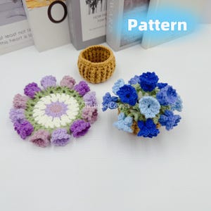 May include: A collection of handmade crochet items, including a small mustard-colored basket, a floral coaster with purple and green accents, and a basket of blue crochet flowers. The word "Pattern" is visible.