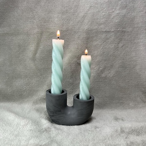 Peut inclure: Un bougeoir en céramique noire en forme de U avec deux bougies torsadées bleu turquoise.