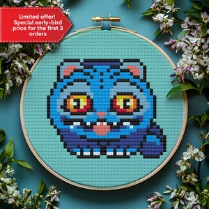 Puede incluir: Un bordado de punto de cruz de un gato azul con ojos amarillos y una lengua rosa, colocado en un aro de madera. El gato está hecho de cuadrados pixelados. El texto "Limited offer! Special early-bird price for the first 3 orders" está en una pancarta roja.