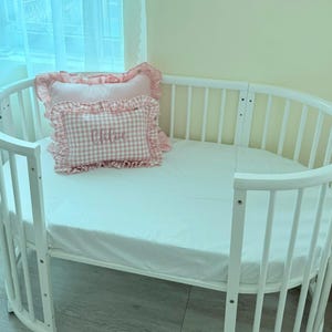 Ruffle baby pillow styled in crib as nursery décor
