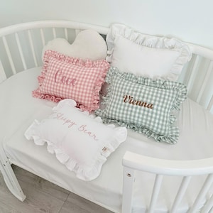 Personalized baby pillow with ruffle trim and embroidered name on crib