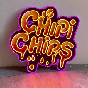 May include: Neon sign with the words "Chi-Chi Chips" in a dripping font. The sign is yellow and orange with a purple outline.