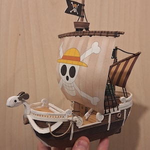 May include: A white ceramic mug with a black handle and the text "But First, Coffee" in a bold, black font. The mug is set against a blurred background, highlighting its clean design.