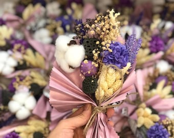 May include: A bouquet of dried flowers featuring cotton, lavender, and other purple and yellow blooms. The bouquet is wrapped in pink paper and tied with twine. The image shows multiple bouquets.