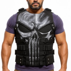 May include: Black tactical vest featuring a white skull design on the chest. The vest has multiple pockets and straps. The person is wearing a purple t-shirt and brown trousers.