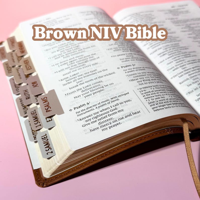 May include: An open brown NIV Bible with white pages featuring black printed text and a tan ribbon bookmark. The side of the pages includes multiple light brown index tabs labeled with book names such as Psalms, Ruth, and 1 Samuel. The text Brown NIV Bible is overlaid in white with a brown outline.