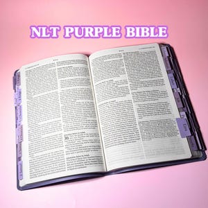 May include: An open NLT Purple Bible with white pages and black text, featuring purple index tabs along the side labeled with book names like 1 Kings, 2 Kings, 1 Chronicles, 2 Chronicles, 1 Samuel, 2 Samuel, Ecclesiastes, Nehemiah, Esther, Job, Psalms, and Proverbs.