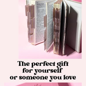 May include: A stack of five hardcover Holy Bibles in gray, brown, white, pink, and sage green. An open Bible displays indexed tabs and printed text. A pink Bible cover features an embossed floral design and the name Kyra in cursive script.