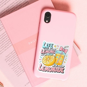 May include: A pink phone case with a colorful sticker that says "Life gave me some lemons but my Jesus he be makin' lemonade." The sticker features a lemon and a glass of lemonade with a straw and bow.