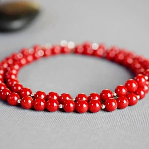 May include: A red coral bead necklace with a double strand of beads.