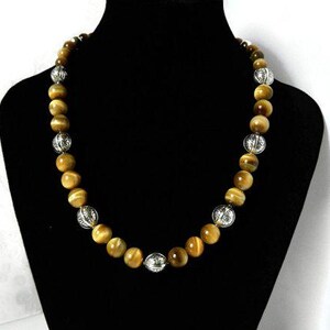 May include: A beaded necklace featuring alternating round, golden-brown tiger's eye gemstones and spherical, silver-toned metal beads with an intricate, embossed floral pattern throughout the entire length of the strand.