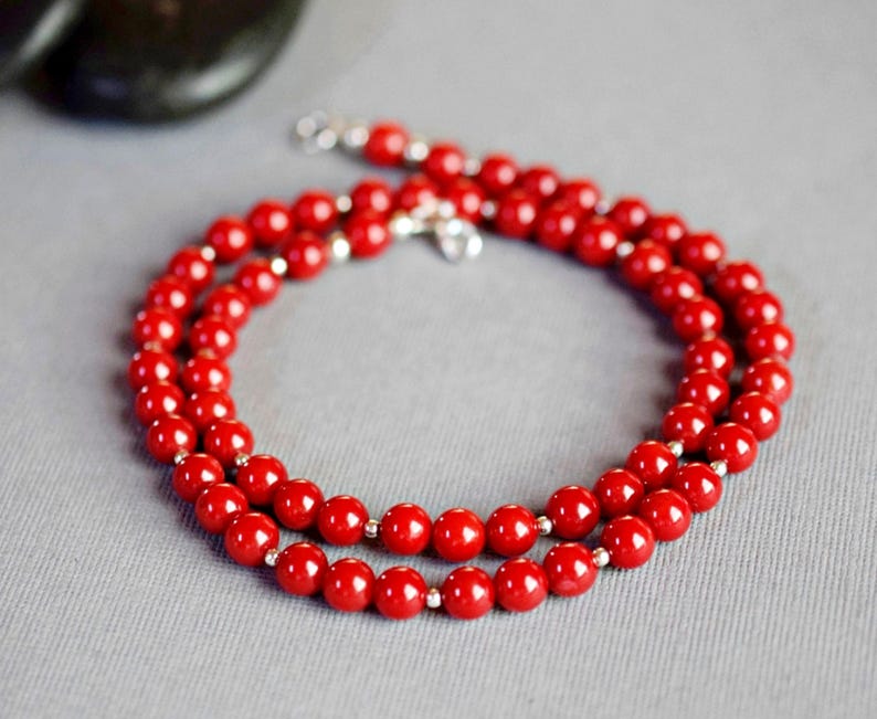 May include: A red beaded necklace with silver clasps. The necklace is made of round beads and is layered twice.