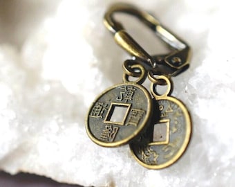 May include: A pair of bronze earrings with Chinese coins hanging from them. The coins have a square hole in the center and Chinese characters around the edge.