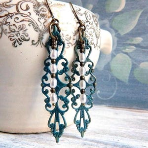 Patina green  and gold filigree earrings with white pearl beads hanging from them