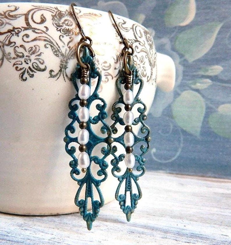 Patina green  and gold filigree earrings with white pearl beads hanging from them
