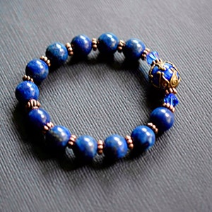 A blue lapis lazuli beaded bracelet with copper spacers and a decorative charm