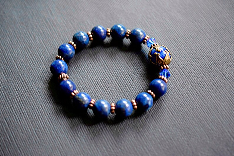 A blue lapis lazuli beaded bracelet with copper spacers and a decorative charm