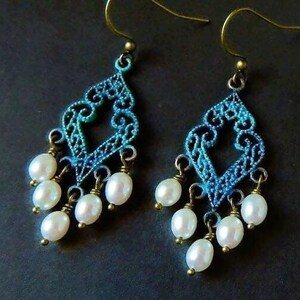 May include: A pair of dangle earrings with a blue and green filigree design and white pearl accents.
