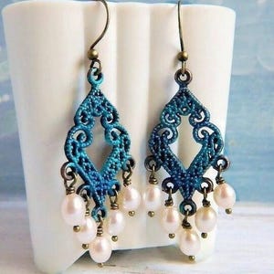 May include: A pair of dangle earrings with a blue and green filigree design and white pearl accents.