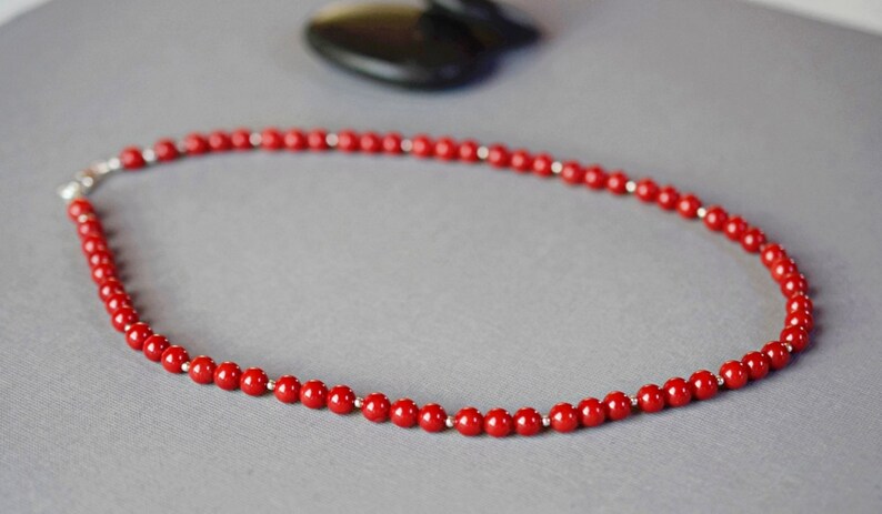 May include: A red coral bead necklace with a silver clasp.