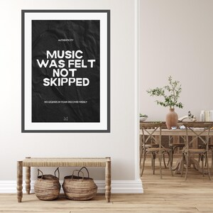 May include: Black and white poster with the text "Music was felt not skipped" and "No legends in your discover weekly". The poster has a crumpled paper texture and is framed in a black frame.