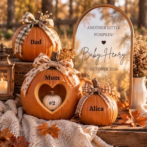 Puede incluir: Tres calabazas naranjas con lazos y texto. Una calabaza tiene un corte en forma de corazón que contiene una pequeña calabaza blanca etiquetada como #2. El texto dice: Dad, Mom, Alica y Another Little Pumpkin! Baby Henry October 2026.