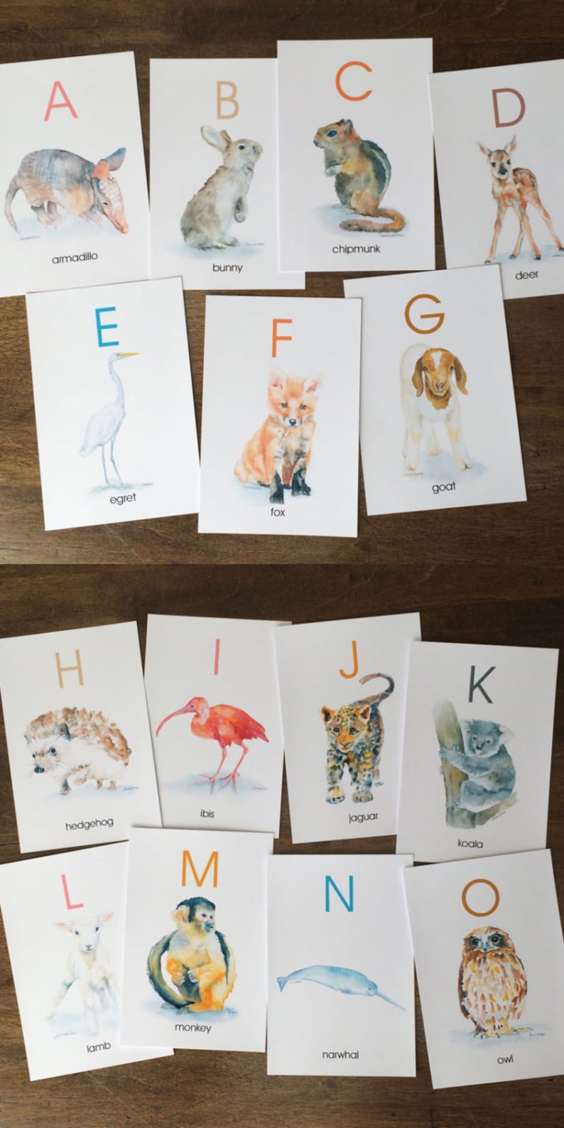 May include: A set of watercolour alphabet cards featuring various animals. Each card displays a letter and an animal illustration, such as an armadillo, bunny, chipmunk, deer, egret, fox, goat, hedgehog, ibis, jaguar, koala, lamb, monkey, narwhal, and owl.