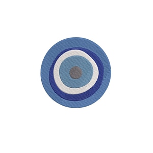 May include: A circular embroidered patch with a stylized eye design. It features concentric circles in shades of blue, white, and grey, creating a layered effect. The design is centred on a white background.
