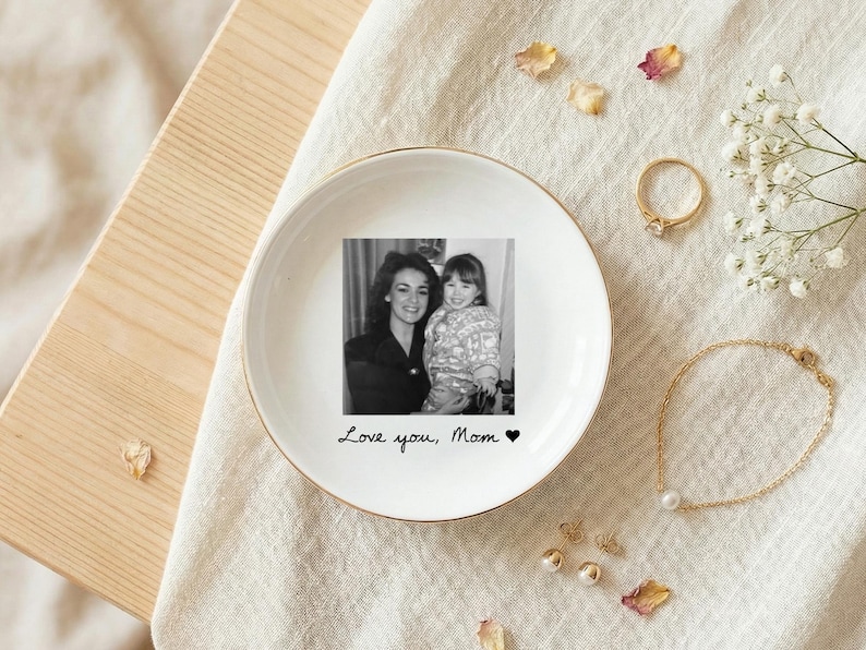 May include: White ceramic trinket dish with a gold rim, featuring a black and white photo of a mother and child. The dish has the handwritten text "Love you, Mom" and a heart symbol.