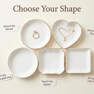 May include: White ceramic jewelry dishes in various shapes: round, heart, square, and a square with a wavy edge. Some have gold trim. The round dish is 3.9 inches in diameter. The heart dish is 3.9 inches wide. The square dish is 3.5 inches wide. The text "Choose Your Shape" is at the top.