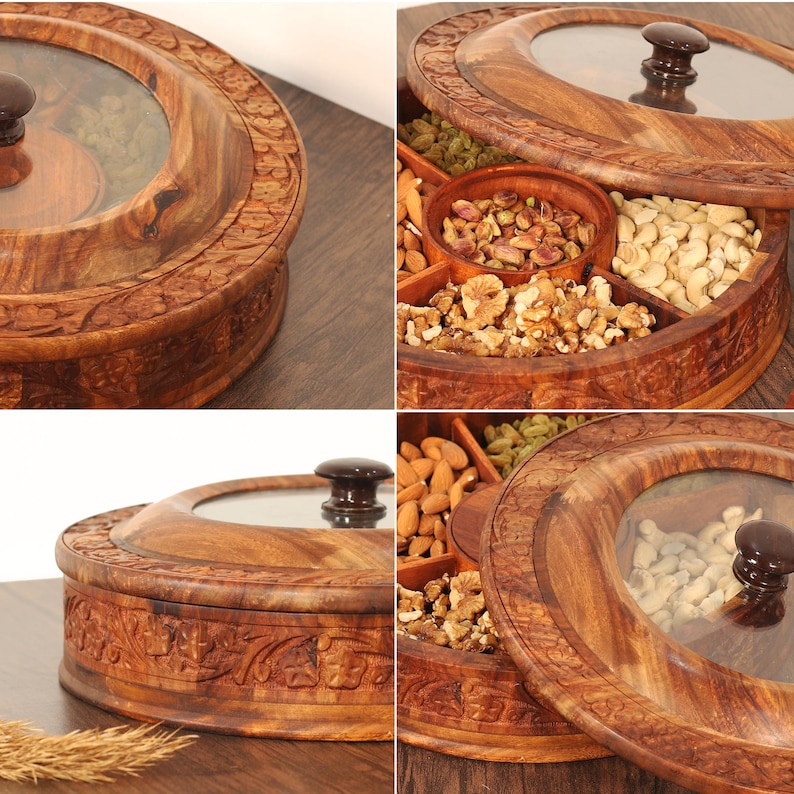 May include: A wooden serving tray with a glass lid and a dark brown knob. The tray is divided into compartments, filled with nuts and dried fruits. The tray has carved floral patterns around the edges. The tray's diameter is approximately 25 cm.