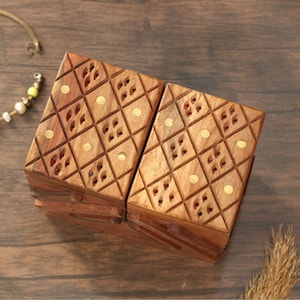 May include: Two wooden boxes with a diamond pattern and brass accents. The boxes are a warm brown color and have small, decorative cutouts. The boxes are open, revealing the interior. The boxes are on a wooden surface.