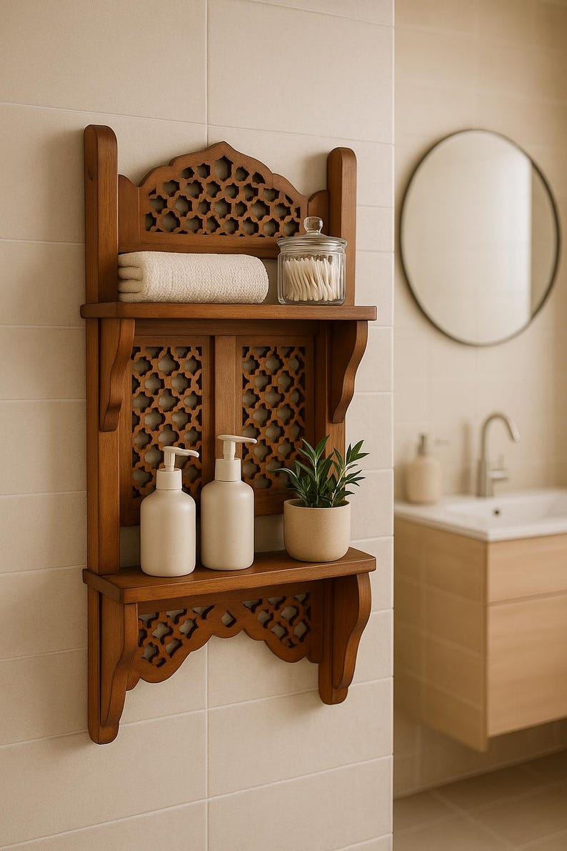 Puede incluir: Estanter&iacute;a de ba&ntilde;o de madera con intrincados dise&ntilde;os calados. La estanter&iacute;a contiene una toalla blanca enrollada, un tarro de cristal con bastoncillos de algod&oacute;n, dos botellas con dispensador blancas y una peque&ntilde;a planta en maceta. La estanter&iacute;a est&aacute; montada en una pared alicatada.