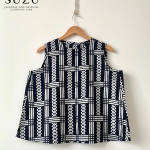 May include: A sleeveless navy blue top featuring a white geometric grid pattern with repeating woven-style lines. The garment is displayed on a wooden hanger. Above the top, the text SUZU JAPANESE AND ORIENTAL CLOTHING LINE is visible.