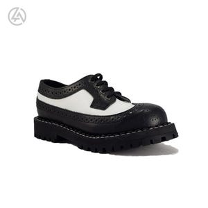May include: Black and white leather oxford shoe with a thick, lugged sole. The shoe features a classic wingtip design with decorative perforations and a contrasting white panel on the upper. The sole is approximately 1.5 inches thick.