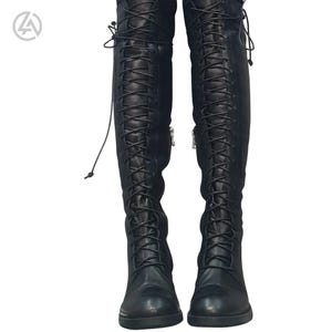 Puede incluir: Un par de botas negras hasta la rodilla con diseño de cordones. Las botas tienen una cremallera en el lateral y están hechas de un material liso similar al cuero. Los cordones suben por la parte delantera de las botas.