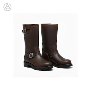 May include: A pair of brown leather motorcycle boots. The boots have a mid-calf height, a rounded toe, and a buckle closure on the side. The soles are black and have a treaded design.