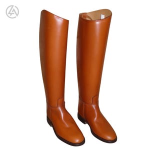 May include: A pair of tall, brown leather riding boots. The boots are knee-high with a smooth, polished finish. They have a classic design, suitable for equestrian activities. The boots are set against a white background.