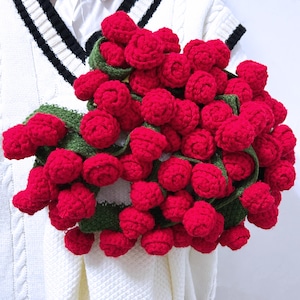 May include: A garland of crocheted red roses with green leaves. The garland is made of yarn and is a handmade craft.