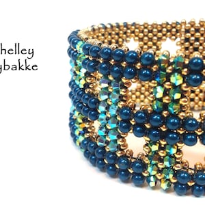 Puede incluir: Un primer plano de una pulsera de cuentas con un patrón geométrico. La pulsera está hecha con cuentas azules, doradas y verdes.