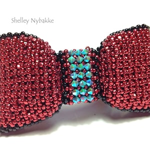 May include: A red beaded bow tie with a black trim and a blue and green iridescent center.