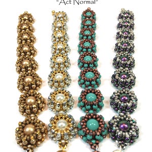 May include: Four beaded bracelets with different color schemes. The bracelets are made with small, round beads in shades of gold, silver, turquoise, and purple. Each bracelet has a small, circular charm attached to the end.