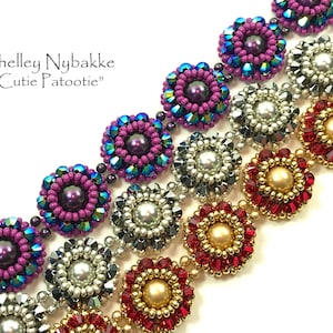 May include: A close-up of a beaded bracelet with a repeating pattern of colorful flower-shaped beads. The beads are in shades of purple, silver, gold, and red. The bracelet is made with small seed beads and larger pearl-like beads.